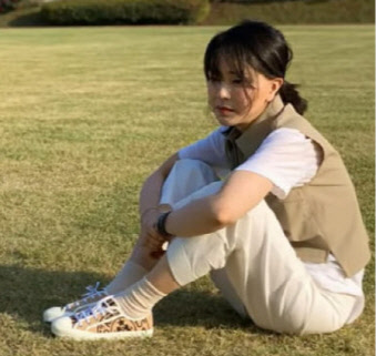 김건희 여사가 지난달 28일 서울 용산 대통령실 청사 앞 잔디마당에서 디올 스니커즈를 착용하고 앉아있다. '건희사랑' 페이스북 갈무리